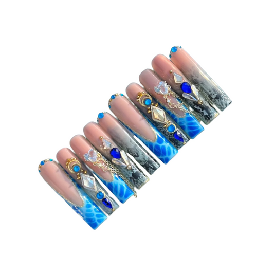 A set of acrylic press-on nails variety of designs including floral and geometric patterns,  in blue and gold colors.